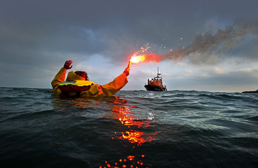 RNLI Crew member in the water with a flare